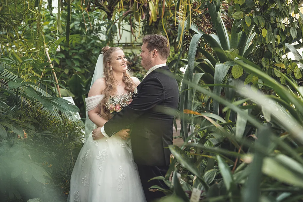 Braut und Bräutigam umgeben von Pflanzen - Mirja John Hochzeitsfotografie